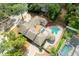 Beautiful aerial view of a home featuring a cabana, unique pool, brick paved driveway, and lush greenery at 100 Crestwood Dr, Longwood, FL 32779