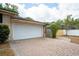 Attached two-car garage with white door and a brick paver driveway at 100 Crestwood Dr, Longwood, FL 32779