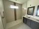 Modern bathroom featuring a sleek walk-in shower, tiled walls, and double vanity at 10043 Dulbecco St, Orlando, FL 32827