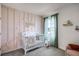 Charming Bedroom features a decorative accent wall, modern crib, and natural light from the nearby window at 1012 Bear Hammock Dr, Umatilla, FL 32784