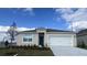 Charming single-Gathering home with a two-car garage, blue entry door, and beautifully landscaped front yard at 1012 Bear Hammock Dr, Umatilla, FL 32784
