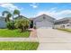 Inviting single-story home with a well-manicured lawn, palm trees, and a wide driveway leading to the garage at 12335 Sumter Dr, Orlando, FL 32824