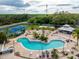 Aerial view of a resort-style pool area with lounge chairs, cabana, and mature landscaping at 135 Orchid Dr, Davenport, FL 33897