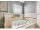 Relaxing bathroom featuring a whirlpool tub with tile surround and a window for natural light at 143 Abbey Hollow Dr, Apopka, FL 32712