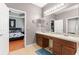 Bright bathroom with double sink vanity and framed mirrors, leading into bedroom with wood floors at 14537 Cheever St, Orlando, FL 32828