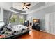 Bedroom with wooden floors, tray ceiling, and a view of the wooded yard through large windows at 14537 Cheever St, Orlando, FL 32828