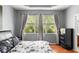 Bedroom with wooden floors, tray ceiling, and a view of the wooded yard through large windows at 14537 Cheever St, Orlando, FL 32828