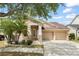 Charming home with a two-car garage, a covered porch, stone accents, manicured landscaping, and palm trees at 14537 Cheever St, Orlando, FL 32828