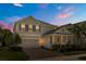 Charming two-story home with a manicured lawn and inviting brick driveway at dusk at 14742 Bahama Swallow Blvd, Winter Garden, FL 34787