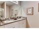 Bathroom featuring double vanity with granite countertop, white cabinetry, and decorative mirrors at 194 Amberwood Way, Umatilla, FL 32784