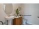 Cozy half bathroom featuring a pedestal sink, wood vanity, toilet, and a decorative plant at 198 Amberwood Way, Umatilla, FL 32784