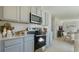 Kitchen with stainless steel appliances, granite countertops, gray cabinets, and a view into an adjacent dining area at 198 Amberwood Way, Umatilla, FL 32784