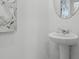 Bright half bathroom with white pedestal sink, round mirror and modern artwork at 2052 Monteverde Ave, Davenport, FL 33837