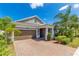 Home exterior featuring a two-car garage, stone accents, manicured landscaping, and brick driveway at 2127 Bay Line Rd, Oakland, FL 34787