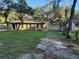 Tan single-story house with brown shutters and dark wood-colored doors and a lawn at 225 W 2Nd St, Chuluota, FL 32766