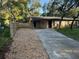 Exterior of home with covered parking spot and driveway, partially surrounded by a wood fence at 225 W 2Nd St, Chuluota, FL 32766