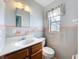 Small bathroom with vanity and toilet, with a small window with white curtain above toilet at 2631 Mcdonald Ter, Mount Dora, FL 32757