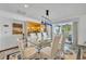 Bright dining room with a glass table, white chairs, modern lighting, and view to the lanai at 3960 Lake Mira Dr Dr, Orlando, FL 32817
