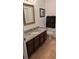 Bathroom featuring a granite vanity, decorative mirror, and dark wood cabinets at 4920 E Lake Cove Blvd, St Cloud, FL 34771