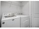 Bright laundry room with modern, white washer and dryer and wire shelf at 5118 Adelaide Dr, Kissimmee, FL 34746