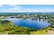A panoramic aerial view of a tranquil lake surrounded by verdant forests and residential areas at 730 S Main Ave, Groveland, FL 34736