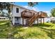 A view of the back of the two-story home with a wooden deck and stairs to the backyard at 730 S Main Ave, Groveland, FL 34736