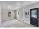 Bright living room featuring neutral walls, carpet floors, and a decorative front door at 730 S Main Ave, Groveland, FL 34736