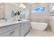 Bright bathroom with a modern tub, a large vanity with double sinks, and a window with natural light at 7905 Jacks Club Dr, Kissimmee, FL 34747