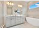 Bright bathroom featuring a modern tub, a large vanity with double sinks, and a window with a view of a blue sky at 7905 Jacks Club Dr, Kissimmee, FL 34747