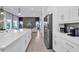 Modern white kitchen featuring an island with marble countertop, stainless steel appliances, and pendant lighting at 7905 Jacks Club Dr, Kissimmee, FL 34747