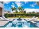 Inviting pool with submerged seating around a fire pit and white lounge chairs surrounded by tropical landscaping under a clear sky at 7905 Jacks Club Dr, Kissimmee, FL 34747