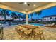 Twilight view of a beautiful pool with ample seating and lush tropical landscaping in the backyard of the estate home at 7905 Jacks Club Dr, Kissimmee, FL 34747