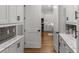 Hallway with white cabinets and marble countertops leading to kitchen with hardwood flooring at 8717 Se 156Th St, Summerfield, FL 34491