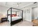 A bright bedroom featuring a four-poster bed, wood floors, tray ceiling, and decorative wall art at 8848 Bismarck Palm Dr, Winter Garden, FL 34787