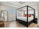 Bright bedroom featuring a four-poster bed, wood floors, tray ceiling, and a neutral color palette at 8848 Bismarck Palm Dr, Winter Garden, FL 34787