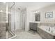 Bathroom with glass enclosed shower, soaking tub, grey cabinets and tile flooring, and neutral walls at 889 Boxelder Ave, Minneola, FL 34715