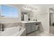 Bright bathroom features a soaking tub, large vanity with sink, and a window with natural light at 889 Boxelder Ave, Minneola, FL 34715