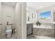 Bathroom features a toilet, soaking tub, gray vanity, window for natural light and tile floor at 889 Boxelder Ave, Minneola, FL 34715