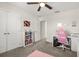 Bright bedroom with a desk, pink chair, and shelving unit with books at 889 Boxelder Ave, Minneola, FL 34715