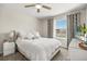 Bright bedroom with a white bedspread, white nightstand, decorative pillows and patterned curtains at 889 Boxelder Ave, Minneola, FL 34715