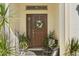 Inviting front entrance featuring a wreath-adorned door, complemented by potted plants and stylish seating at 889 Boxelder Ave, Minneola, FL 34715