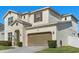 A close view showcasing the tan garage door of a two-story home with a well-maintained lawn at 889 Boxelder Ave, Minneola, FL 34715