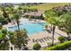 Stunning aerial view of a community pool with spacious sun deck, lush landscaping and tropical palms at 889 Boxelder Ave, Minneola, FL 34715