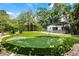 Expansive backyard with a putting green, inground pool, outdoor kitchen and mature trees at 906 Alhambra Ct, Orlando, FL 32804