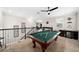 Game room features a pool table, ceiling fan, and staircase with decorative wrought iron at 9574 Meadow Hunt Way, Winter Garden, FL 34787