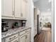 Butler pantry with white cabinets, granite counters, and stainless steel refrigerator at 9574 Meadow Hunt Way, Winter Garden, FL 34787