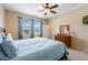 Bright bedroom featuring a ceiling fan, dresser, and sunny windows with blue curtains at 1023 Hermosa Way, Kissimmee, FL 34744