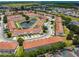 Wide aerial of residential area featuring pond and red tile roofs, surrounded by lush greenery at 1180 S Beach Cir, Kissimmee, FL 34746