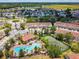 Aerial view of the community featuring a sparkling pool, clubhouse, tennis courts, and lush landscaping at 1180 S Beach Cir, Kissimmee, FL 34746