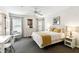Bright bedroom featuring neutral walls, carpet, a desk, and a bed with a golden patterned throw and multiple windows at 1180 S Beach Cir, Kissimmee, FL 34746